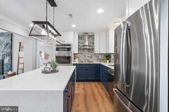 kitchen with visible vents, wall chimney range hood, white cabinetry, backsplash, and stainless steel appliances