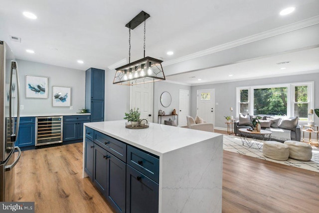 kitchen featuring blue cabinets, freestanding refrigerator, beverage cooler, open floor plan, and light wood-style floors