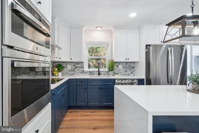 kitchen with a sink, blue cabinetry, stainless steel appliances, white cabinetry, and backsplash