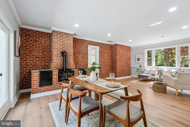 dining room with brick wall, crown molding, a wood stove, baseboards, and light wood-style floors