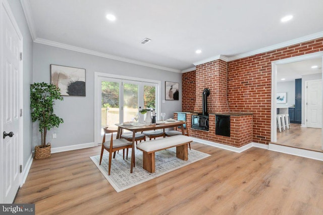 dining area with light wood-style floors, a wood stove, and visible vents