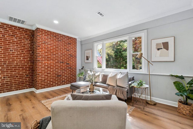living room featuring baseboards, crown molding, brick wall, and visible vents