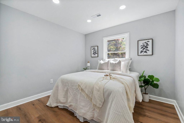 bedroom with baseboards, recessed lighting, wood finished floors, and visible vents