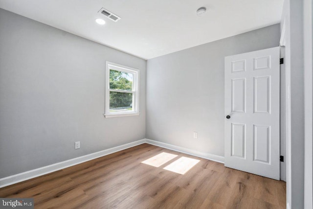 empty room featuring recessed lighting, baseboards, visible vents, and wood finished floors