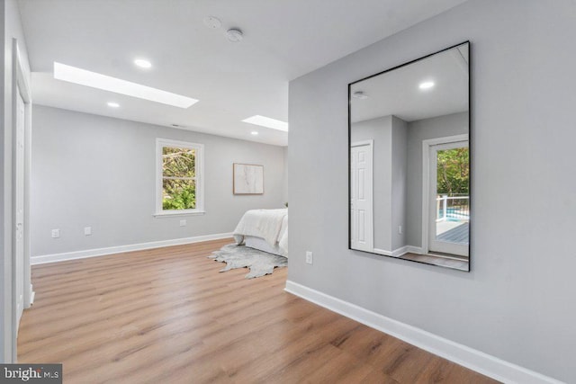 empty room with light wood-style floors, baseboards, plenty of natural light, and a skylight