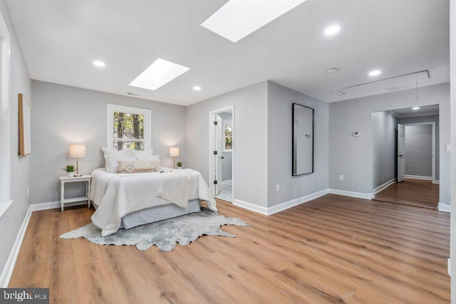 bedroom featuring attic access, a skylight, wood finished floors, baseboards, and recessed lighting