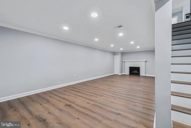 unfurnished living room featuring recessed lighting, ornamental molding, wood finished floors, and stairway