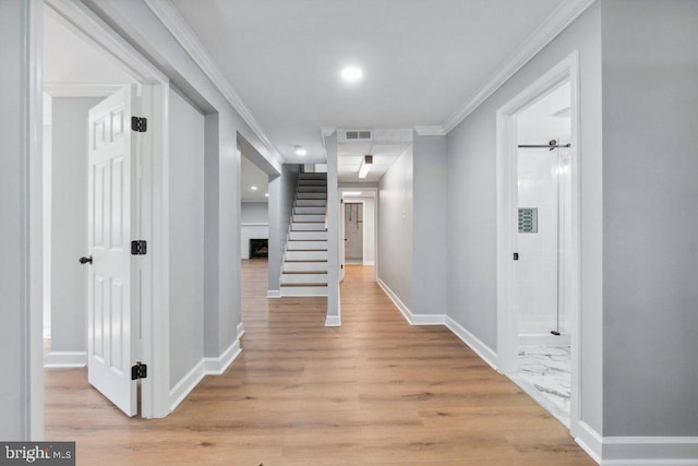 corridor featuring visible vents, crown molding, baseboards, stairs, and light wood-style flooring