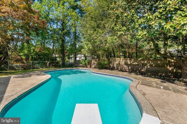 view of swimming pool featuring a fenced in pool, a fenced backyard, a diving board, and a patio