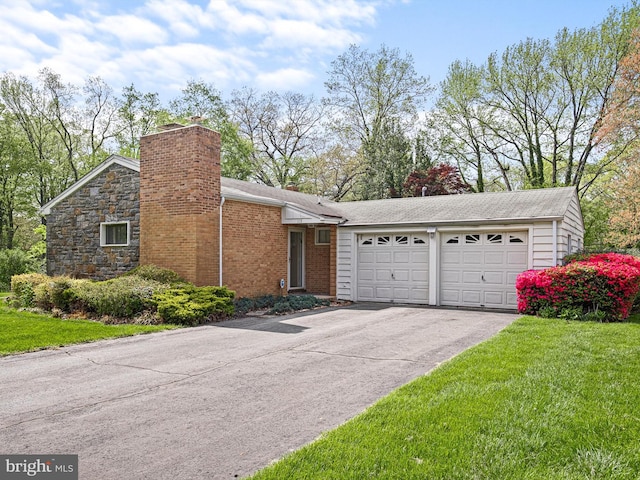 view of front facade featuring brick siding, a garage, a front yard, a chimney, and driveway
