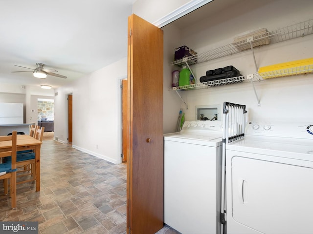 laundry area featuring laundry area, baseboards, ceiling fan, stone finish floor, and washer and clothes dryer