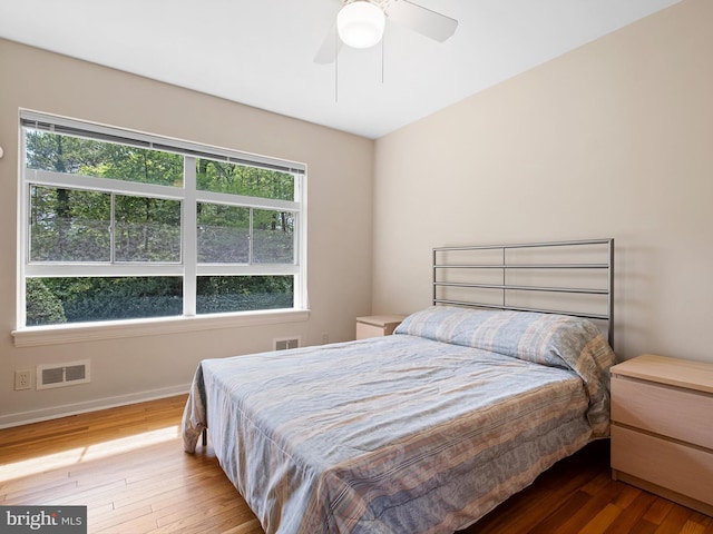 bedroom with baseboards, wood finished floors, and visible vents