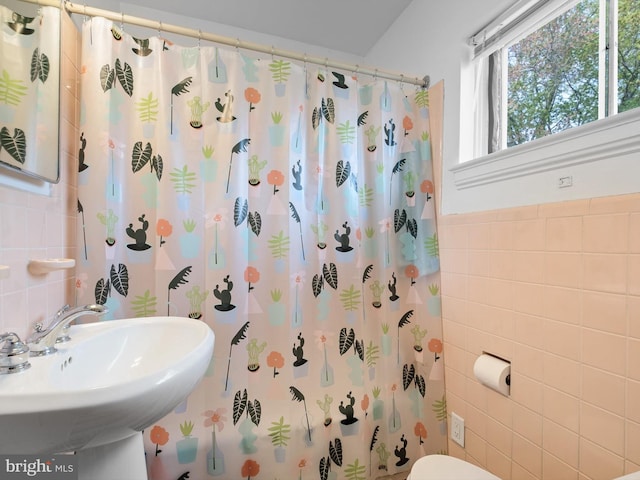 bathroom featuring a sink, curtained shower, toilet, and tile walls