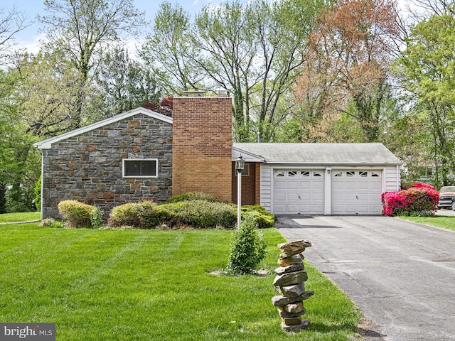 mid-century modern home featuring aphalt driveway, a chimney, a front lawn, and a garage