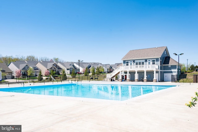 view of swimming pool with stairway, a residential view, fence, and a patio area