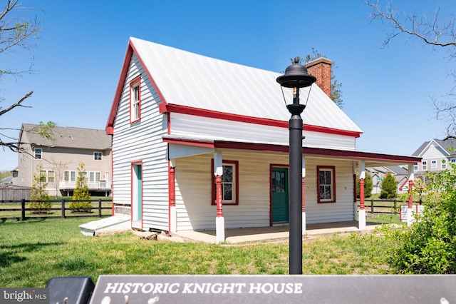 view of front of property featuring a chimney, a porch, and metal roof
