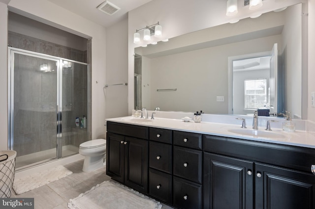 bathroom with a shower stall, double vanity, toilet, and tile patterned floors