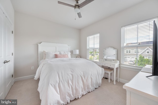 bedroom with light carpet, baseboards, and a ceiling fan