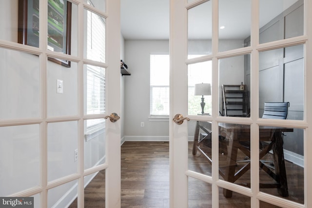 corridor featuring baseboards, wood finished floors, and a desk