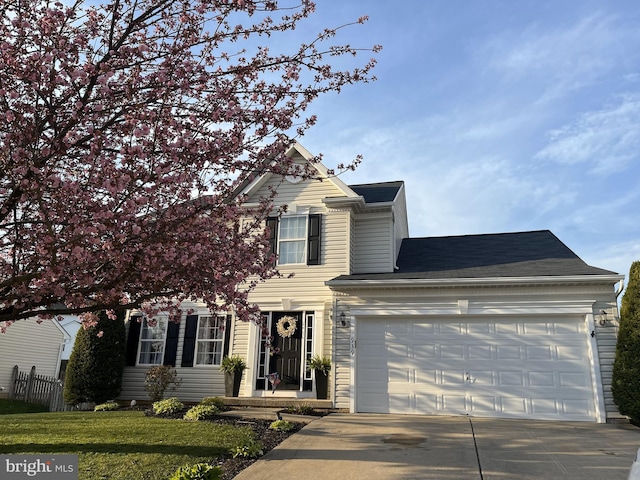 traditional-style home with a front lawn, driveway, an attached garage, and fence