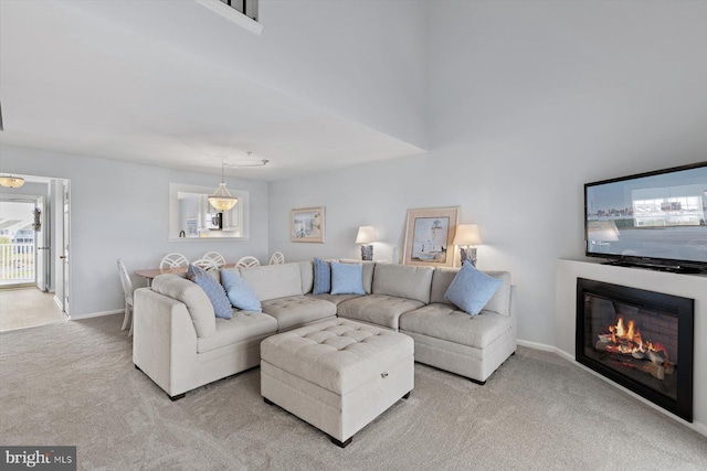 carpeted living area with baseboards and a glass covered fireplace