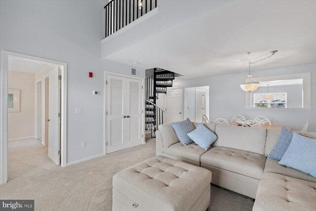 carpeted living room with baseboards, visible vents, and stairway