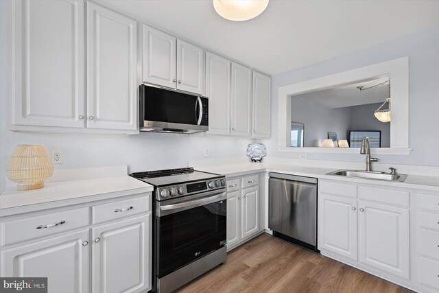 kitchen with a sink, appliances with stainless steel finishes, white cabinetry, and light countertops