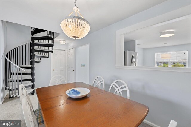 dining space with stairway, baseboards, an inviting chandelier, and light carpet
