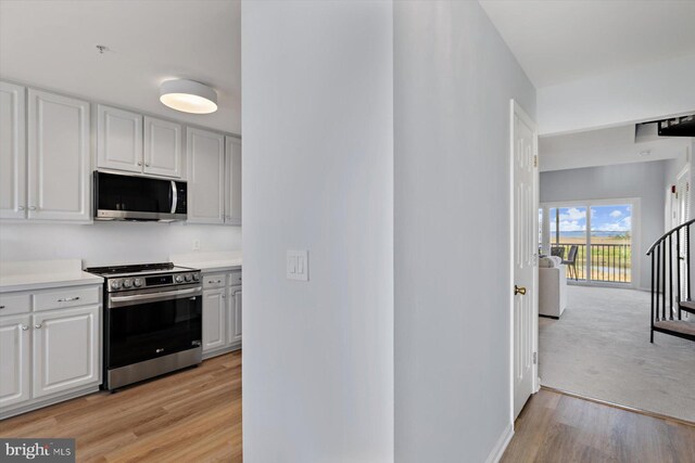 kitchen with light countertops, light wood finished floors, white cabinetry, and stainless steel appliances