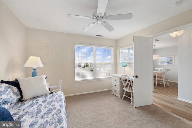 living area with baseboards, ceiling fan, light colored carpet, and visible vents