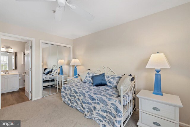 bedroom featuring a sink, ensuite bath, carpet floors, baseboards, and a closet