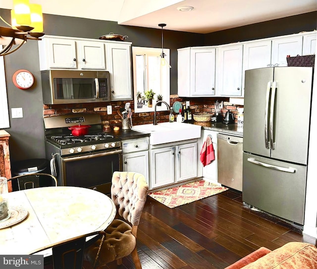 kitchen featuring appliances with stainless steel finishes, a sink, decorative backsplash, dark wood-style floors, and white cabinets