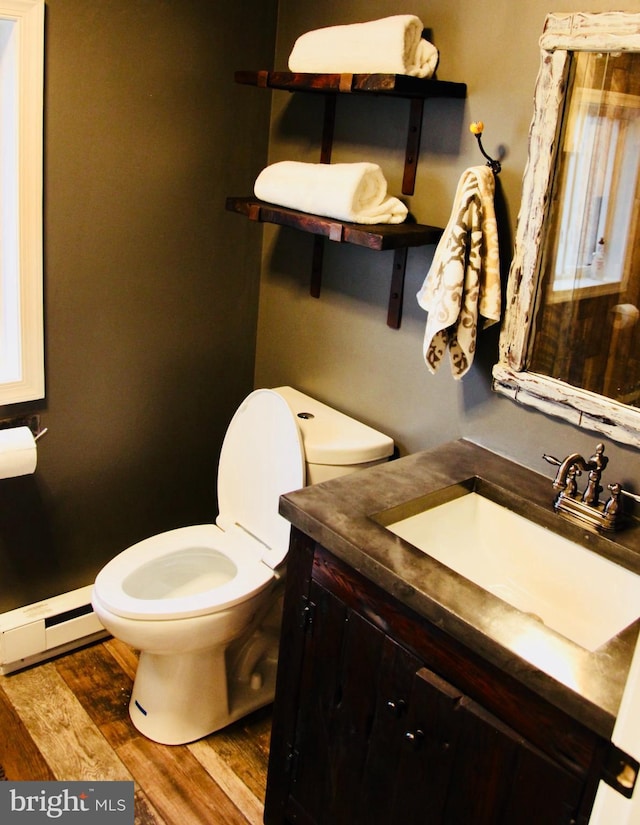 bathroom with a baseboard heating unit, toilet, wood finished floors, and vanity