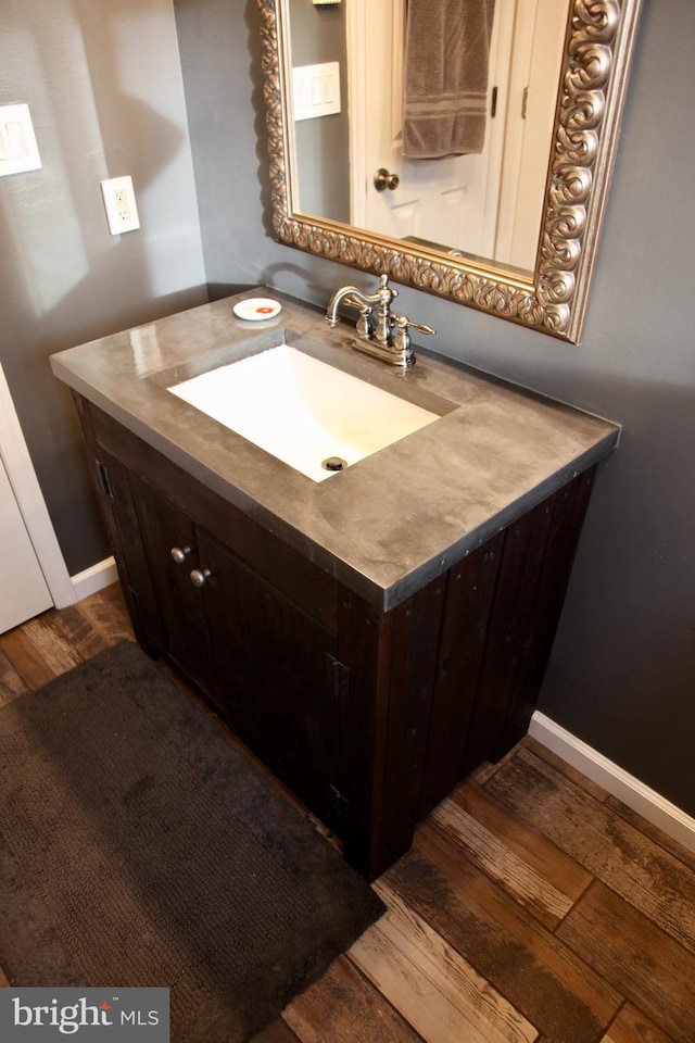 bathroom with wood finished floors, vanity, and baseboards
