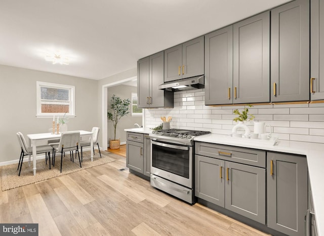 909 Snure Rd, Silver Spring, MD 20901 - kitchen with stainless steel gas range, gray cabinetry, under cabinet range hood, decorative backsplash, and baseboards