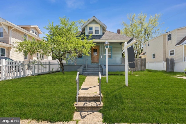 view of front of home featuring fence, a chimney, a porch, and a front lawn