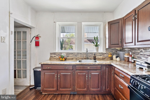 kitchen with tasteful backsplash, black range with gas cooktop, dark wood-style floors, and a sink