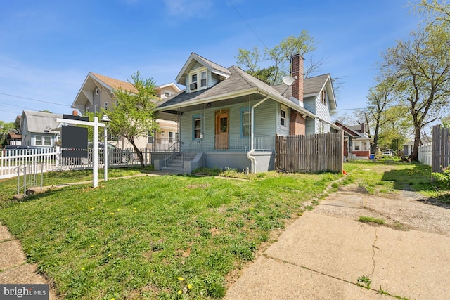 bungalow featuring fence, a front yard, a chimney, and a porch
