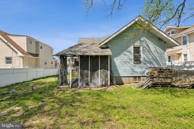 rear view of house featuring fence, a yard, and a sunroom