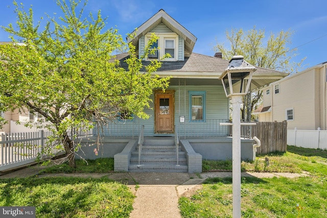 view of front facade with fence, a porch, and a shingled roof