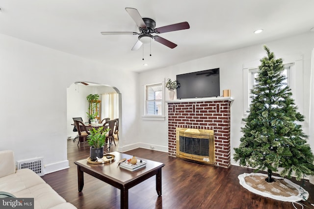 living room with recessed lighting, a fireplace, visible vents, arched walkways, and wood finished floors