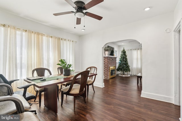 dining space featuring arched walkways, ceiling fan, wood finished floors, and baseboards