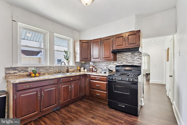 kitchen featuring black range with gas cooktop, under cabinet range hood, decorative backsplash, and a sink