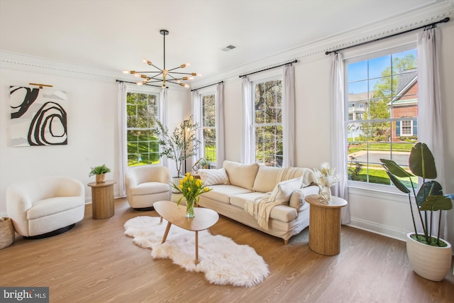 living area with a healthy amount of sunlight, wood finished floors, a chandelier, and baseboards