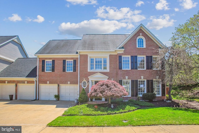 view of front of home featuring a front lawn, driveway, roof with shingles, and brick siding
