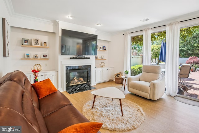 living room with visible vents, wood finished floors, a premium fireplace, and ornamental molding