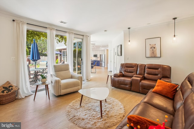 living area featuring ornamental molding, visible vents, and light wood-style floors