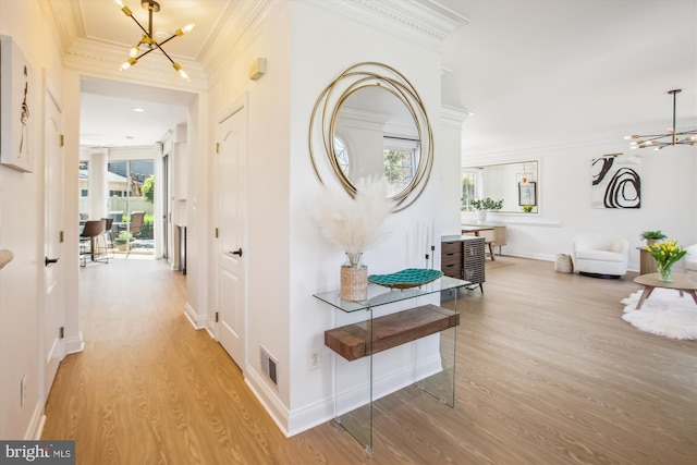 hallway with crown molding, visible vents, a notable chandelier, and light wood-type flooring