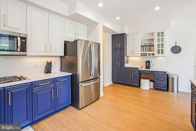 kitchen featuring white cabinetry, stainless steel appliances, light wood-style flooring, and baseboards