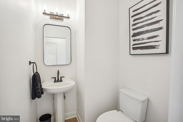 half bath with baseboards and toilet